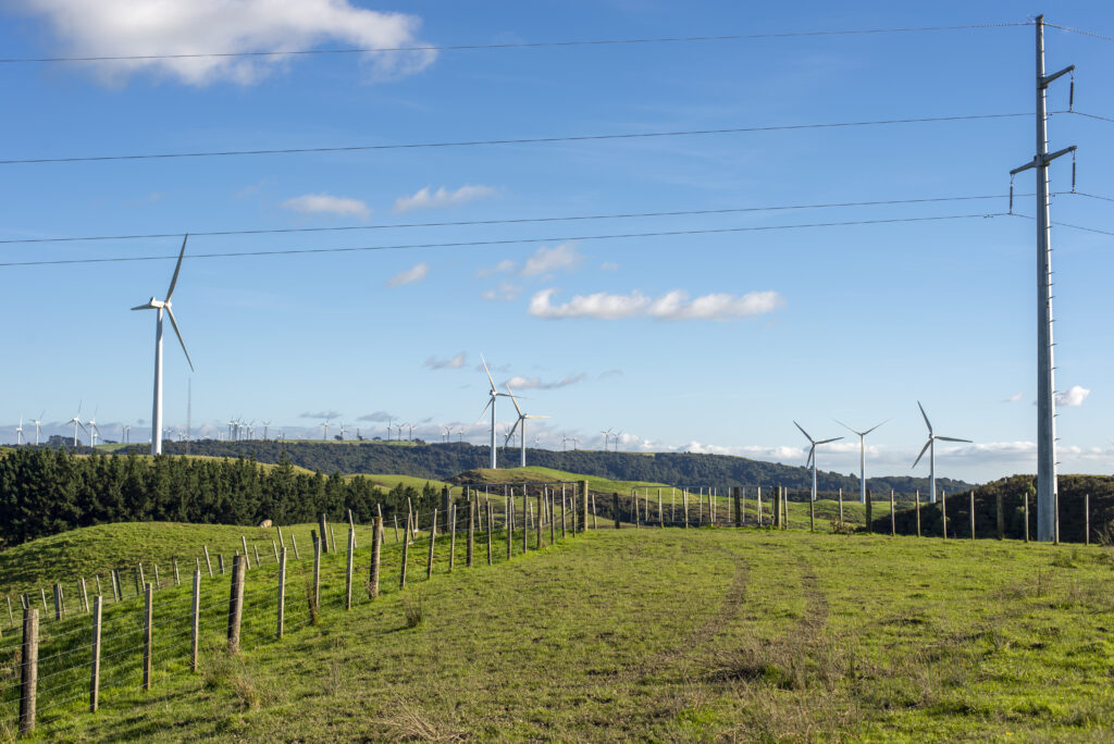 A farmland with wind turbines in the background